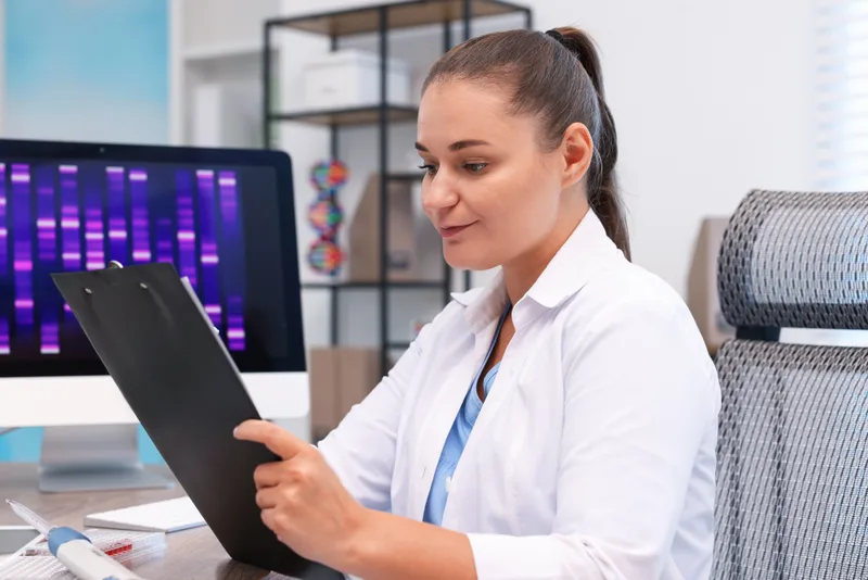 A genetics researcher working at a laboratory table with a clipboard