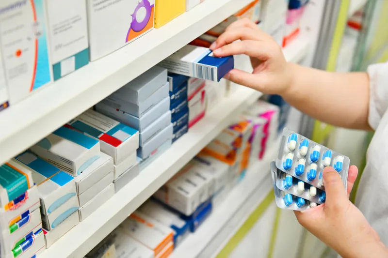 A pharmacist holding a medicine box and a capsule pack