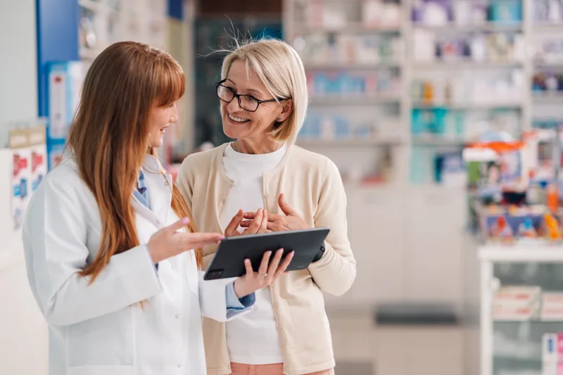 A pharmacist showing information on a tablet to a customer