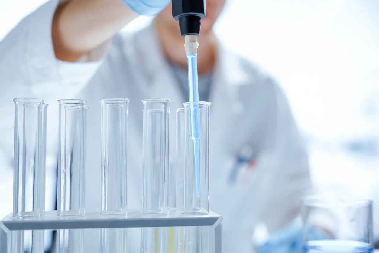 Lab professional carefully pipetting a sample into a test tube